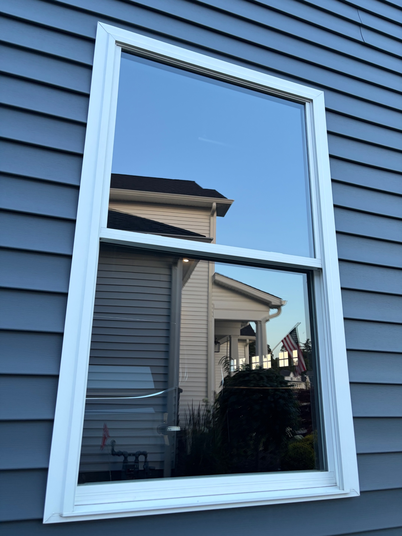 Spotless double-hung window on blue siding home